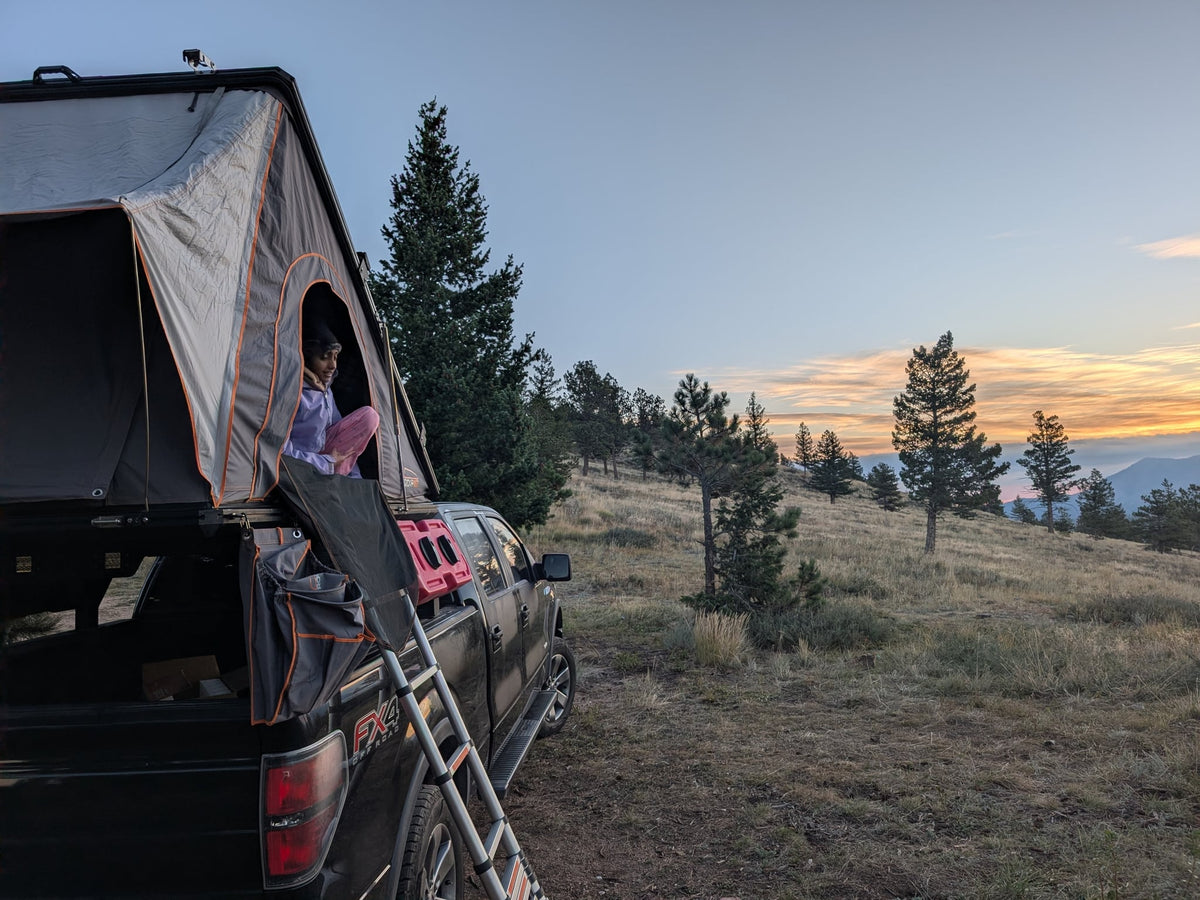 RV rental truck with a rooftop tent. A camper enjoys a scenic sunset from above — photo 1