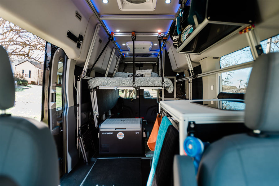 seen through its open rear doors. Perfect for camping.|Interior view of a modern rv rental camper van. Features a raised bed in back
