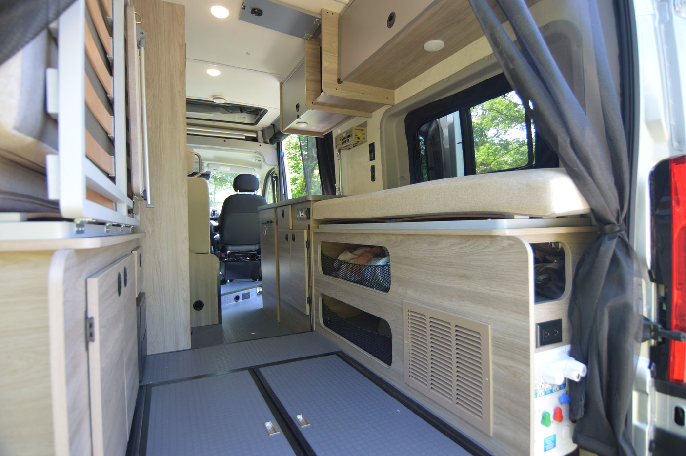 Interior of an RV rental, showing a functional layout with wood cabinetry, cushioned seating, and ample storage.