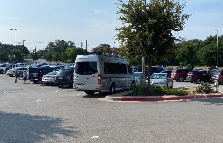 is parked on a paved driveway.|A bright silver RV rental van is parked on a paved lot — photo 4