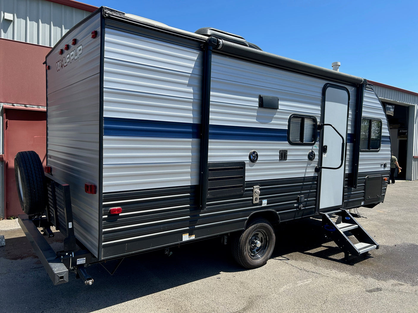 A sleek WOLF PUP travel trailer, ideal for an rv rental getaway. It features an awning and rear-mounted spare tire.