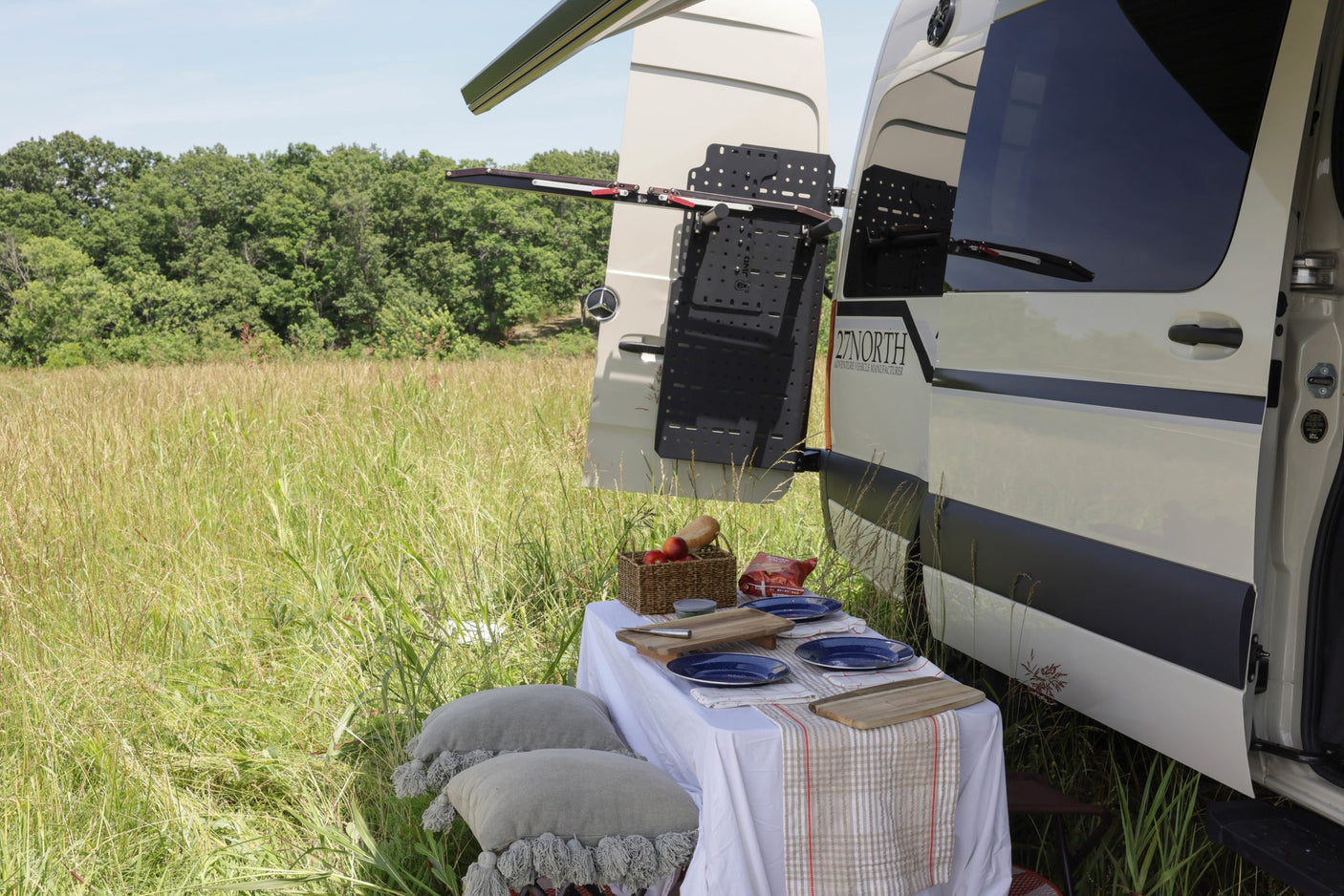 Picnic beside a 27 NORTH camper van with gear rack, ideal for an rv rental outdoor adventure.