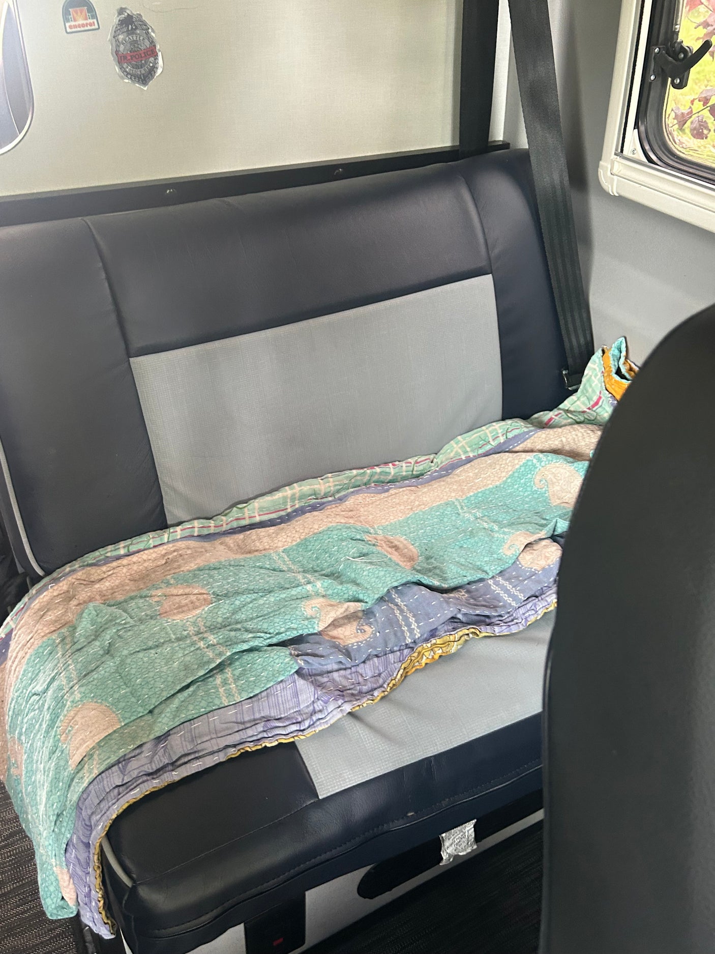 Cozy RV rental interior with a two-tone seat and a colorful blanket, perfect for road trip adventures. Seattle sticker visible.