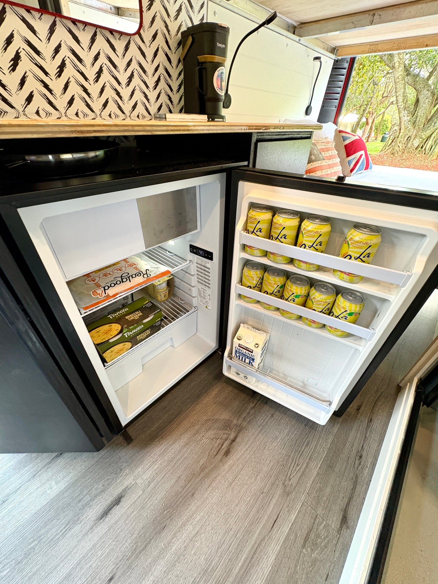 The well-stocked compact fridge and coffee station in this RV rental are ready for van life adventures, with milk, drinks, and snacks.