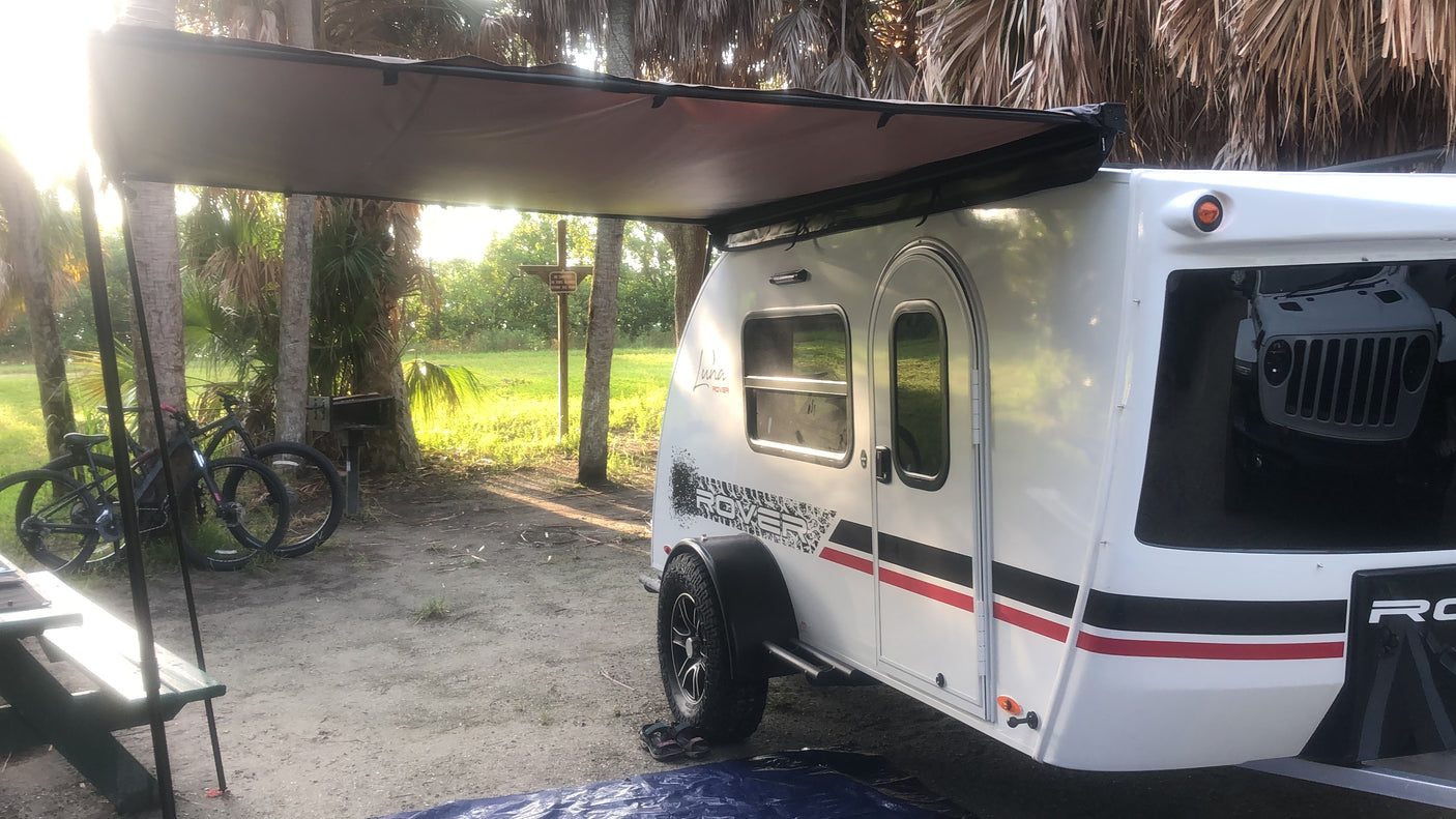 Teardrop rv rental at a sunny campsite with bikes and a picnic table, perfect for outdoor camping adventures.