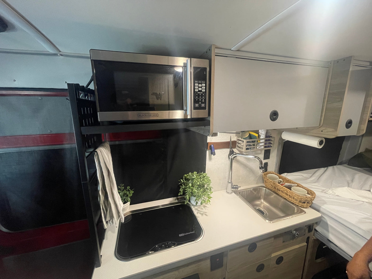 Compact rv rental kitchen with microwave, sink, and stovetop, showcasing efficient space use. Ideal for road trips.