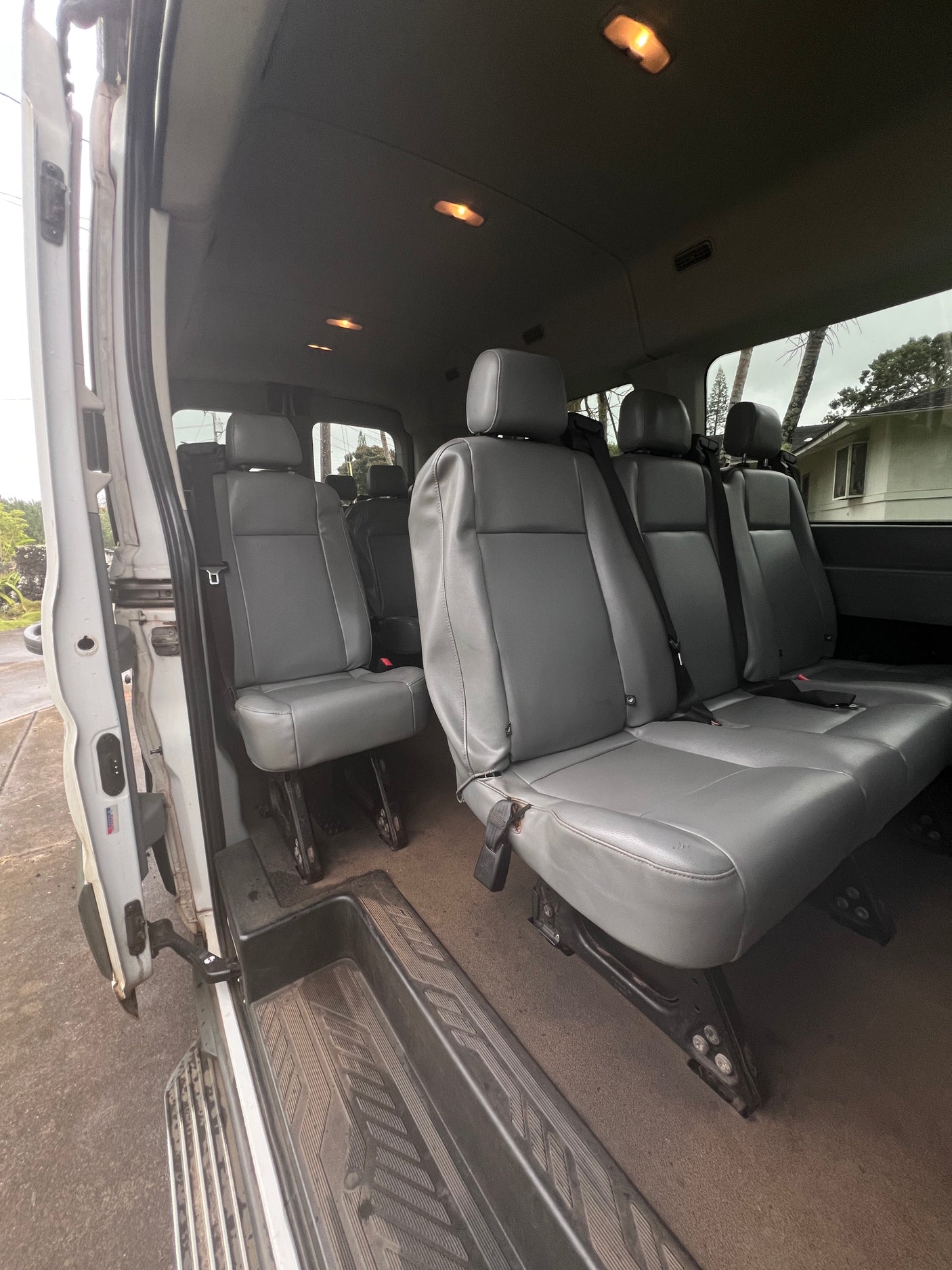 RV rental interior: A bright, spacious passenger van with multiple rows of grey seats, seen through the open side door.