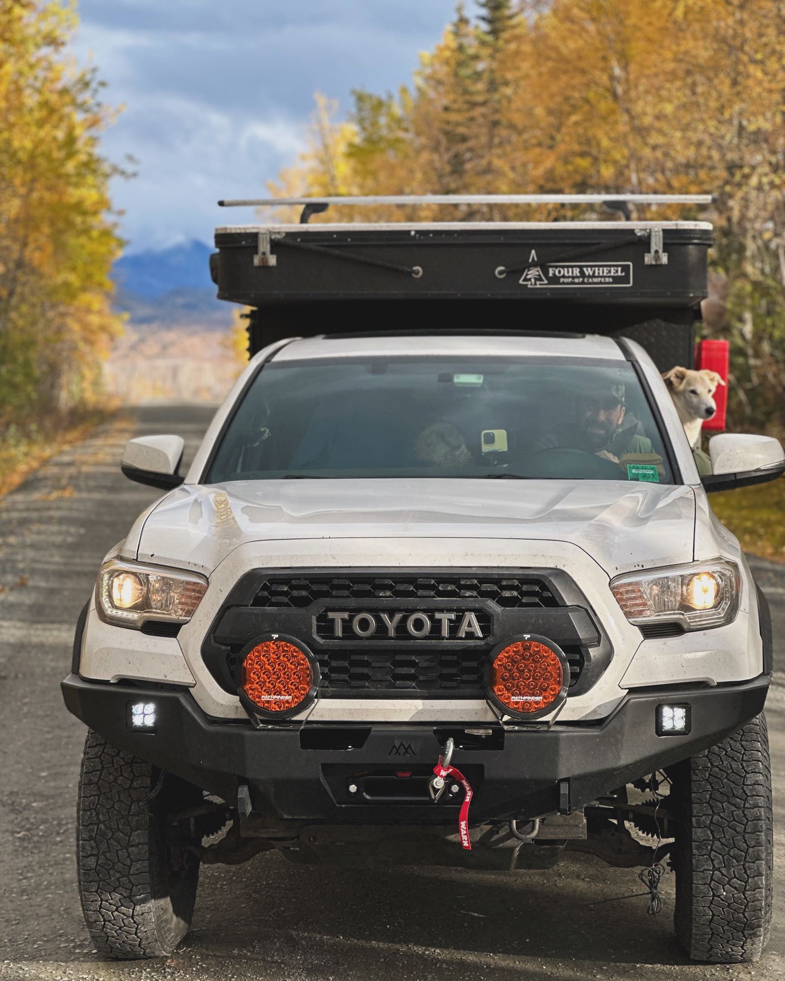 A white Toyota Tacoma truck with a pop-up camper