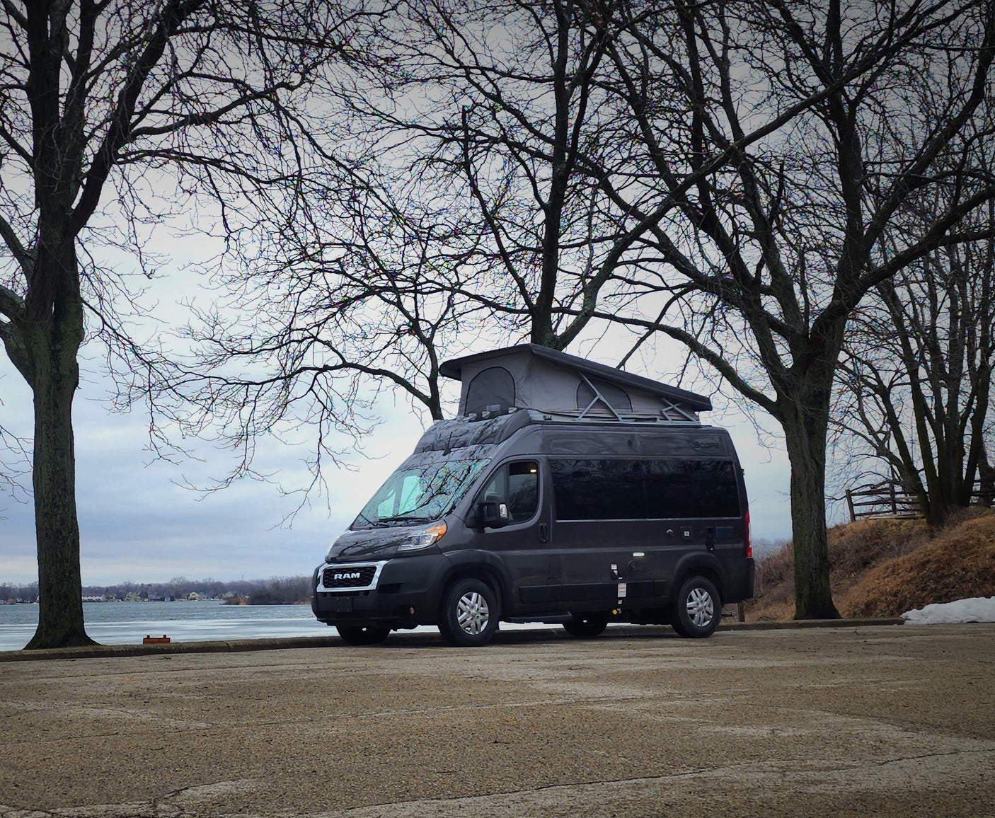 and a window view of serene water.|Inside an RV rental: a ladder to the pop-top bed