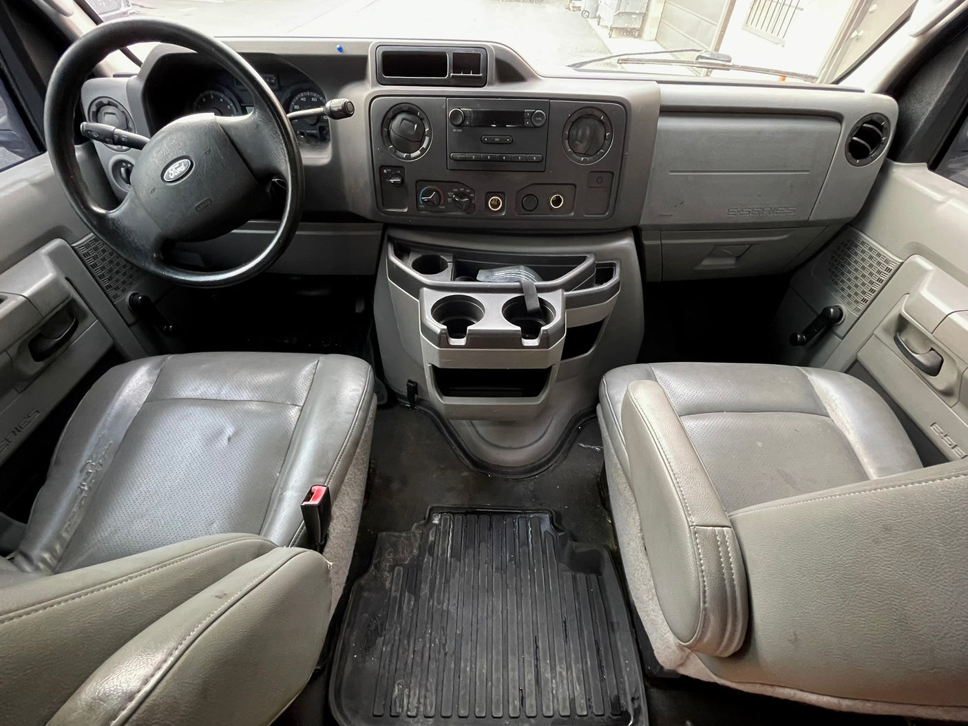 View inside a Ford E-Series van, typical for rv rental, showing the gray dashboard, steering wheel, and front seats.