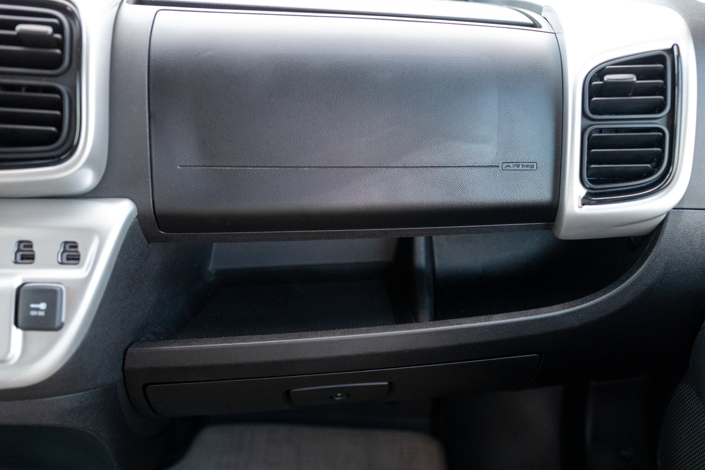 Passenger dashboard of an RV rental, featuring air vents, an 'AIR bag' glove box, and convenient multi-level storage with power outlets.