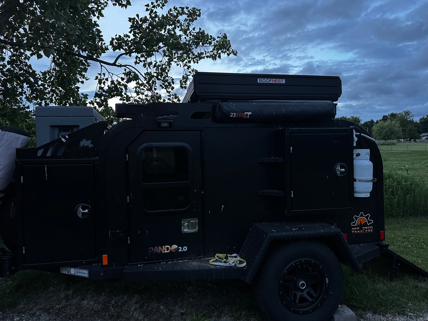 A robust black Pando 2.0 off-grid trailer, equipped with a Roofnest rooftop tent, ideal as an RV rental for outdoor adventures.