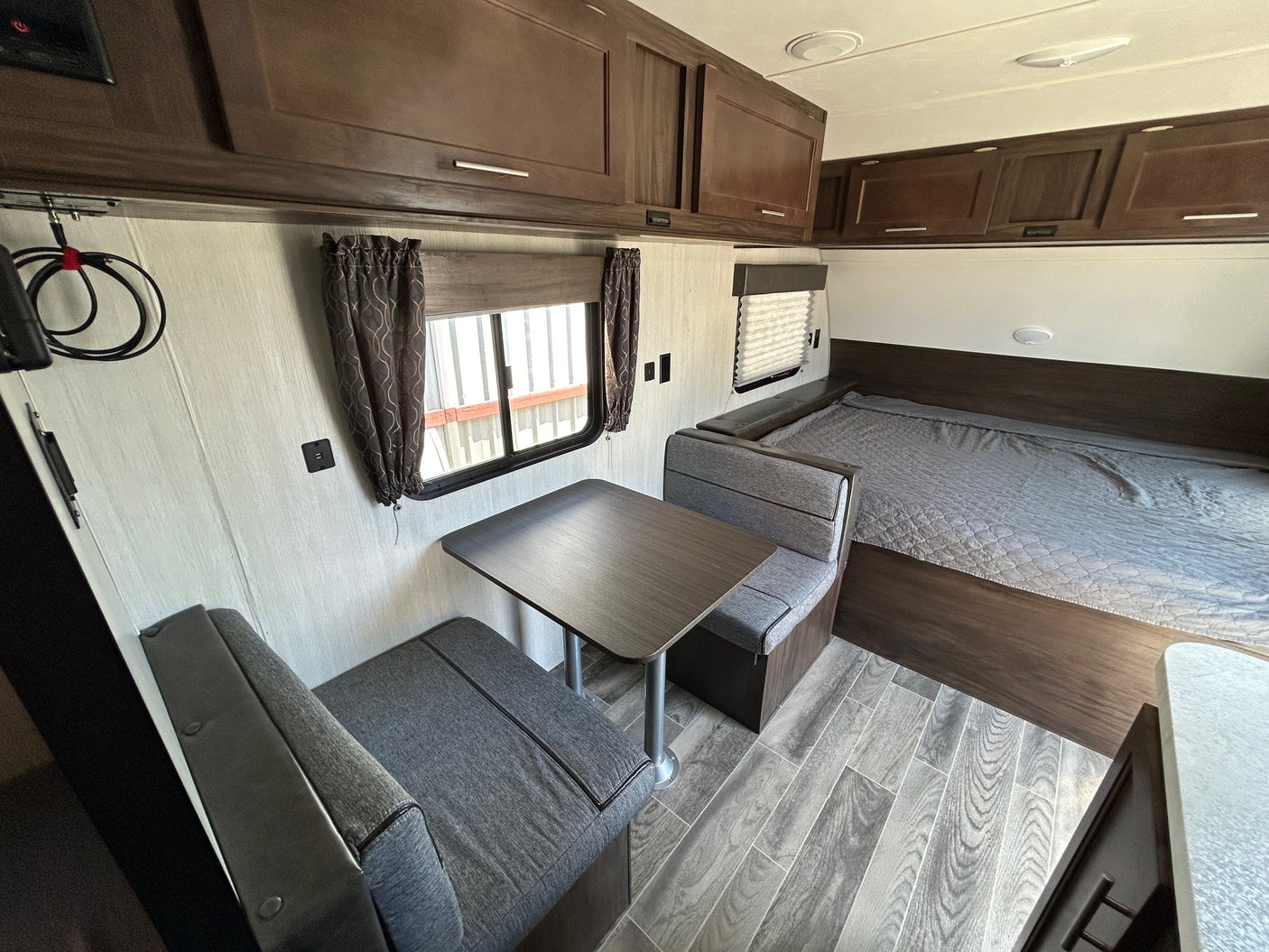 **rv rental** interior: a functional layout with a dinette, main bed, and extensive overhead cabinets.