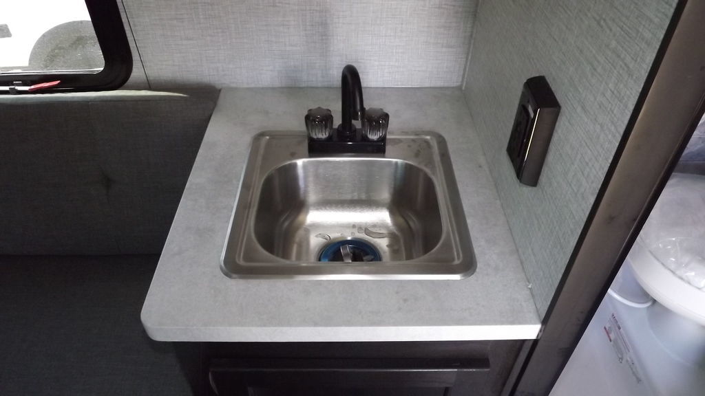 mounted in a dark wooden frame in an RV.|Compact RV rental interior featuring a wet bath with toilet/shower combo