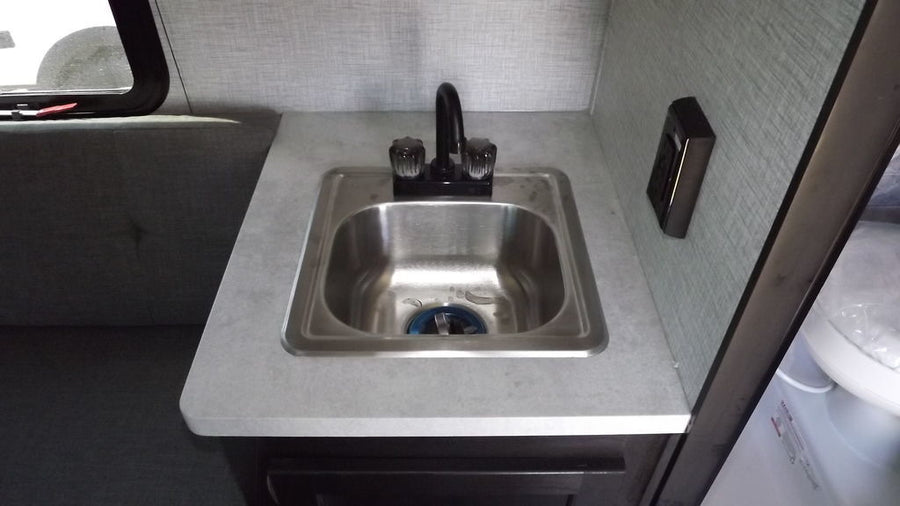 mounted in a dark wooden frame in an RV.|Compact RV rental interior featuring a wet bath with toilet/shower combo
