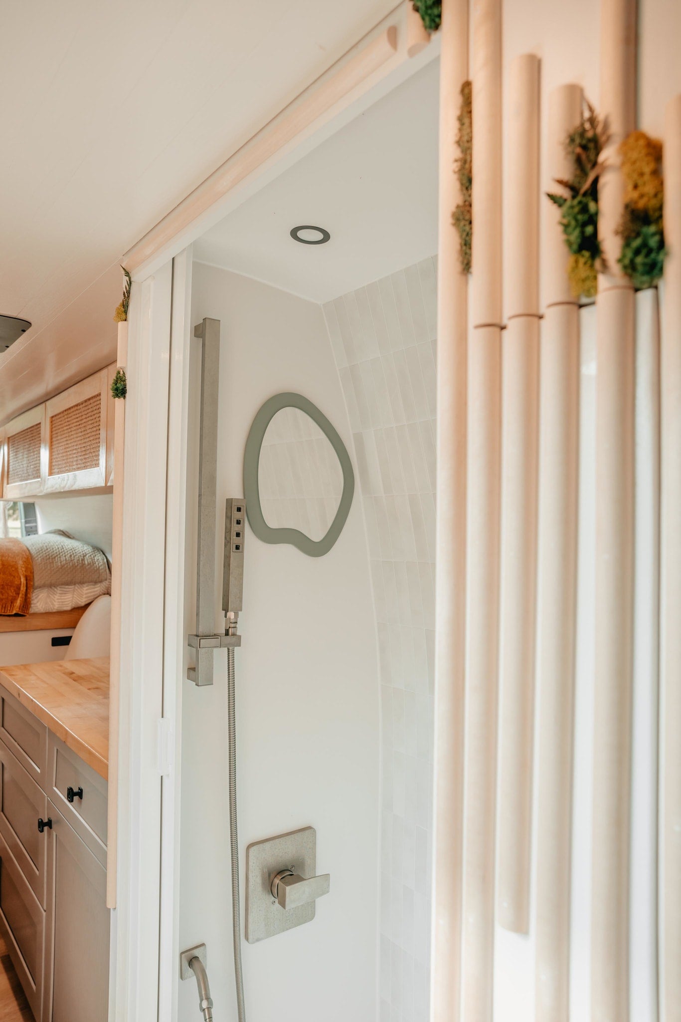 built-in table extending to sand. Sunlight illuminates modern design.|Bright RV rental interior: custom kitchen with macrame fruit holder