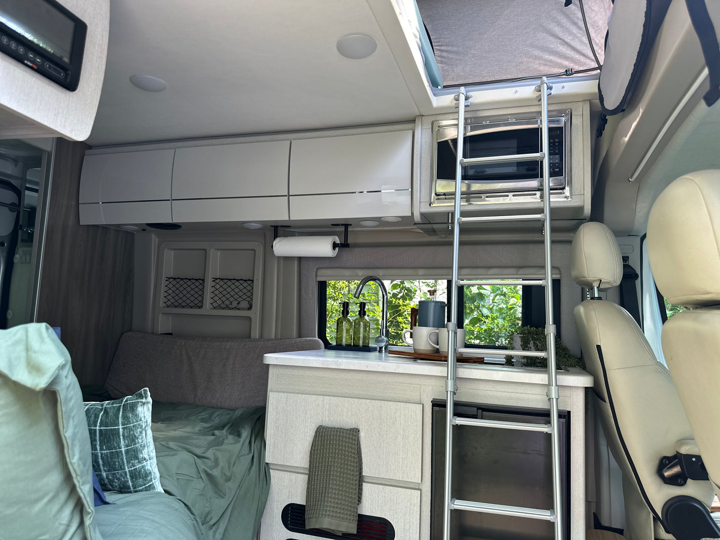Step inside this RV rental: a modern kitchen, comfortable bed, and a ladder leading to a pop-top bunk for adventure.