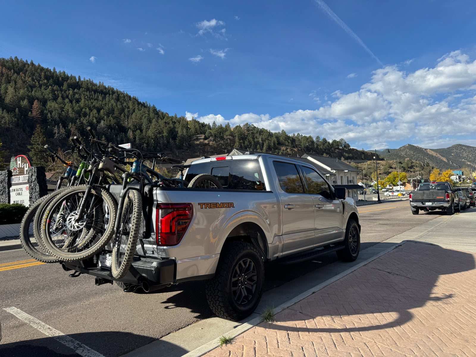 Silver F-150 Tremor truck with bikes, an outdoor alternative to RV rental, in a scenic mountain town.