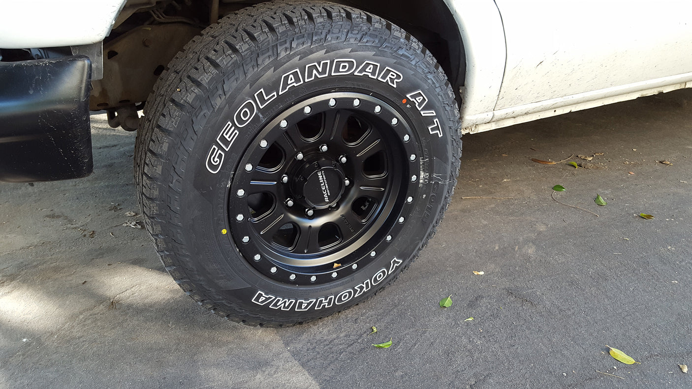 A pristine Yokohama GEOLANDAR A/T tire and black Raceline wheel on an RV rental, ready for any adventure.