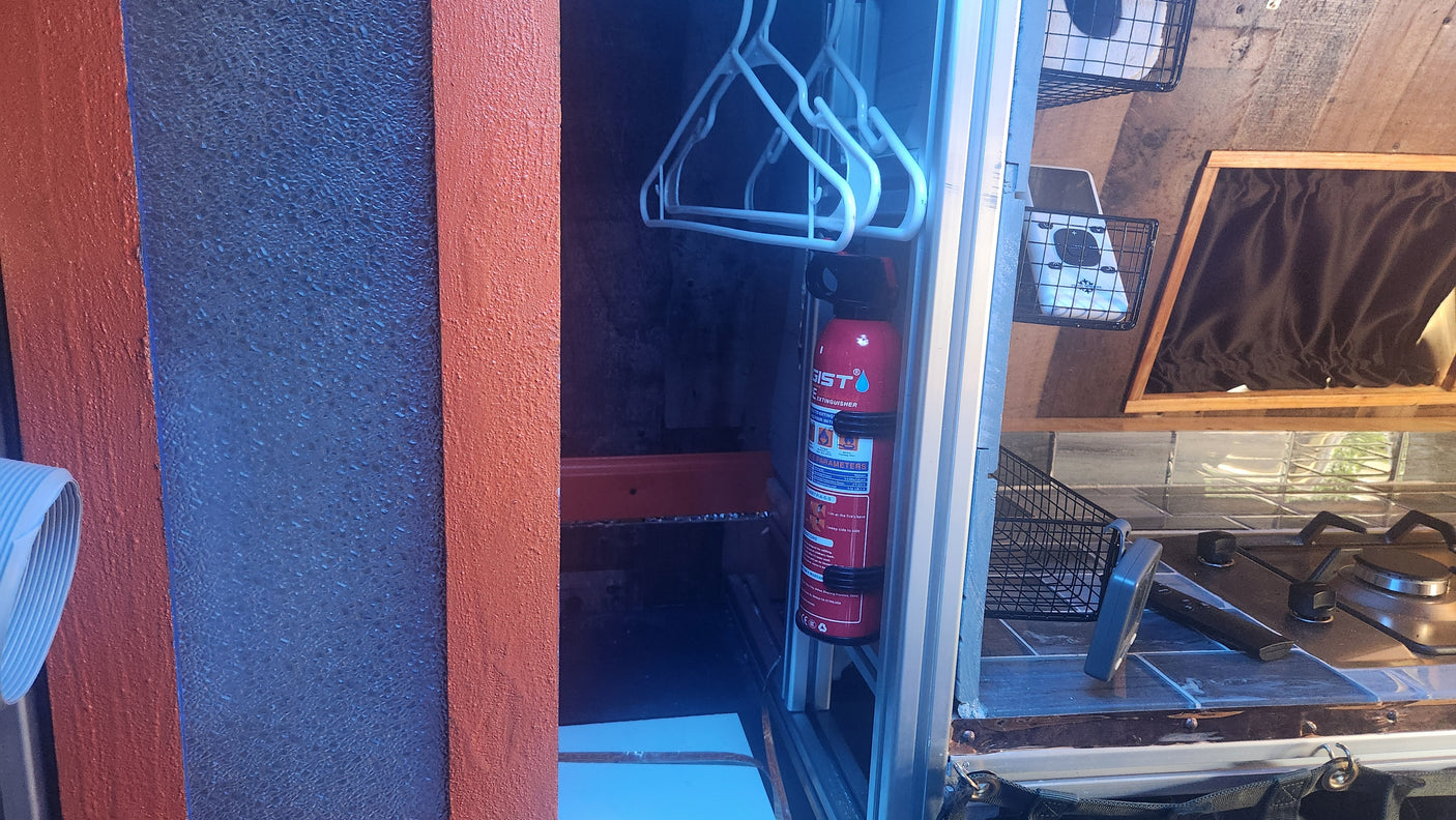 Inside an **rv rental**: A red fire extinguisher is mounted, with white hangers, a gas stove, and storage baskets visible.