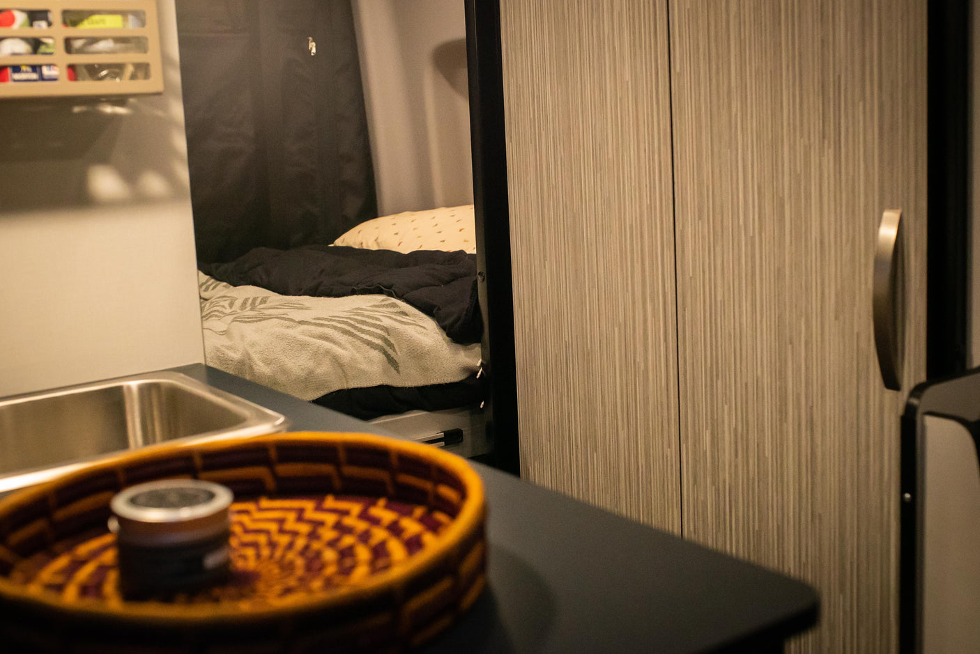 RV rental interior shows a compact kitchenette with sink, and a cozy bed area with blankets, highlighting practical amenities.