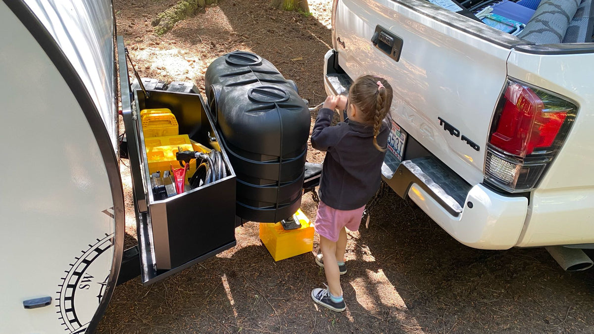 A child helps set up a compact rv rental trailer behind a white truck at a campsite. Ready for adventure! — photo 19