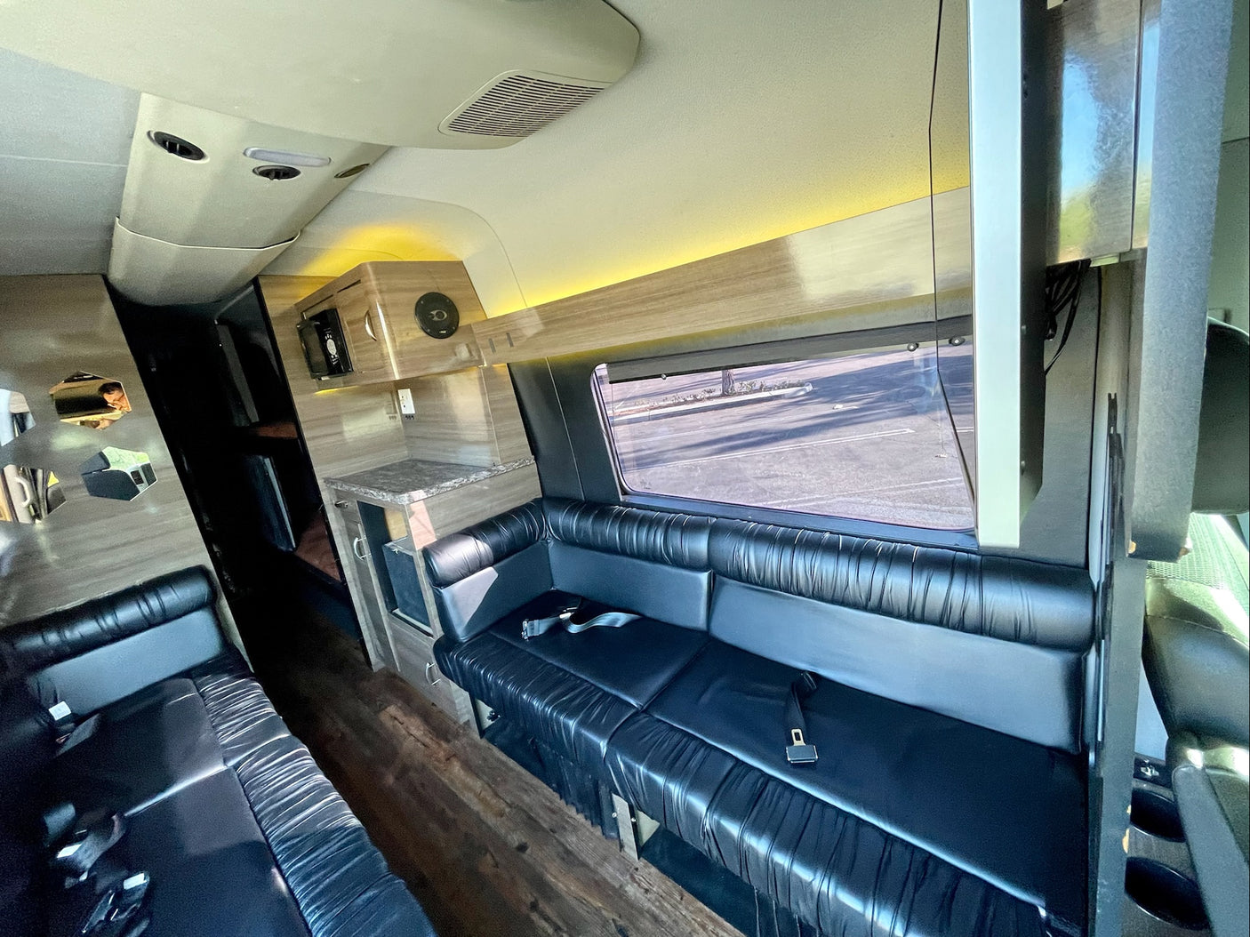 Luxury RV rental interior with spacious black leather seating, a counter area, and warm ambient lighting.