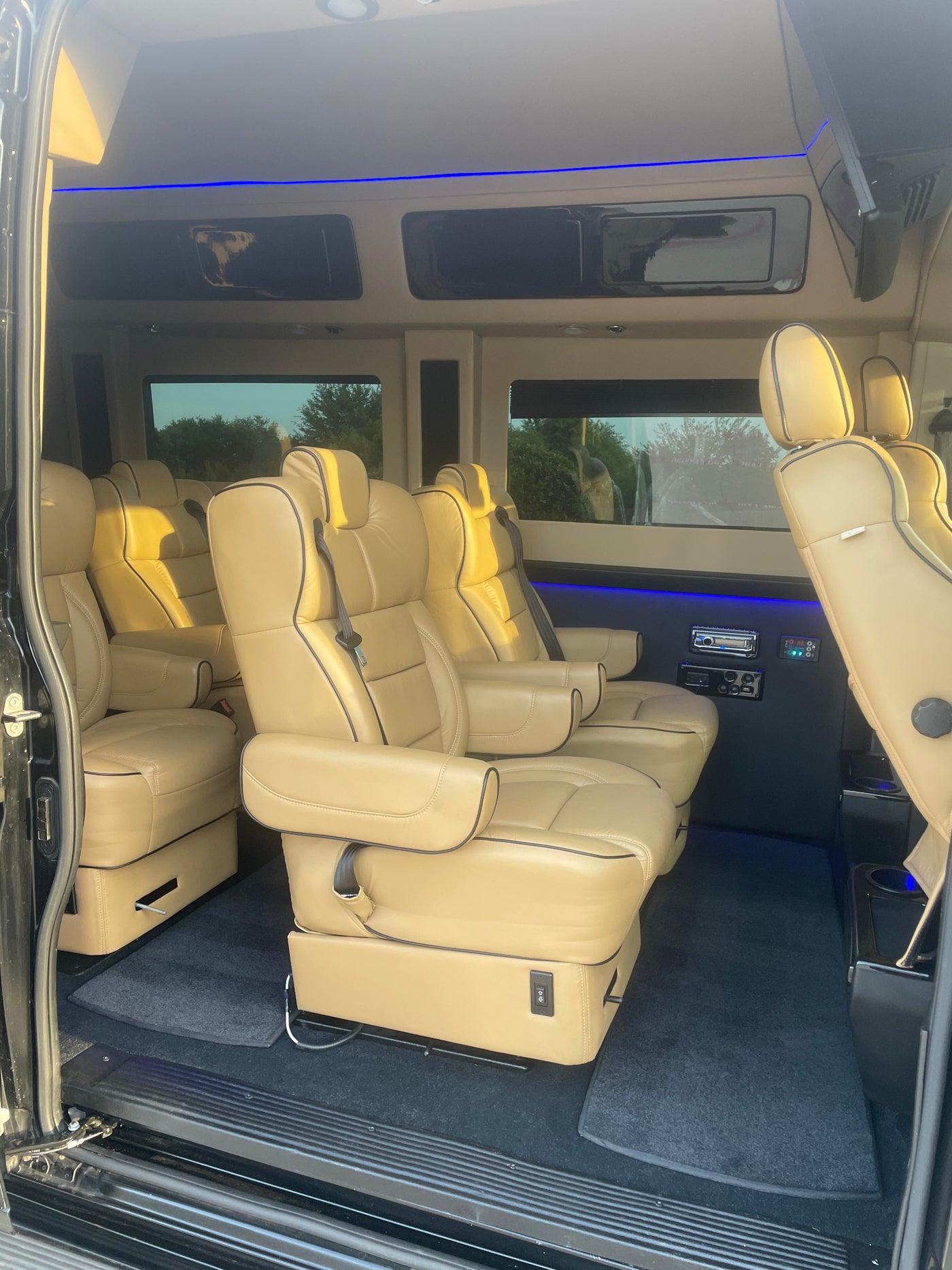 Experience luxury travel! This spacious RV rental features plush tan leather seating, blue LED lighting, and monitors for comfort. — photo 4
