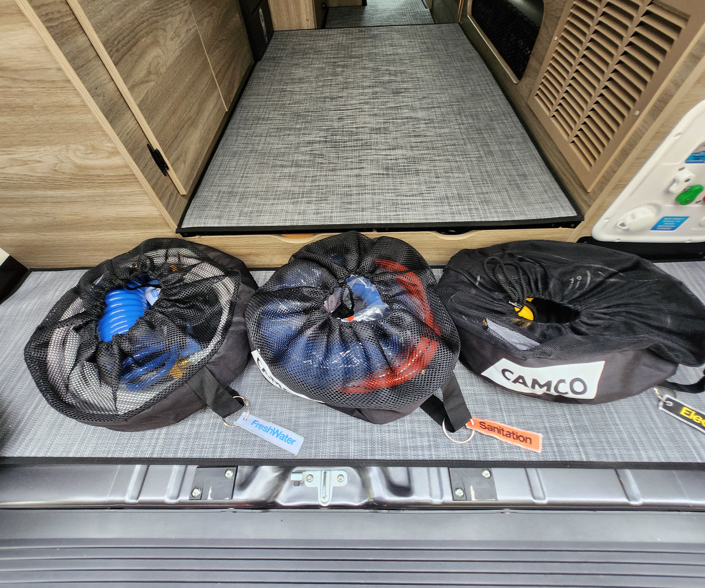 Organized RV rental gear: FreshWater, Sanitation, & Electrical hoses/cables in mesh bags for easy access.