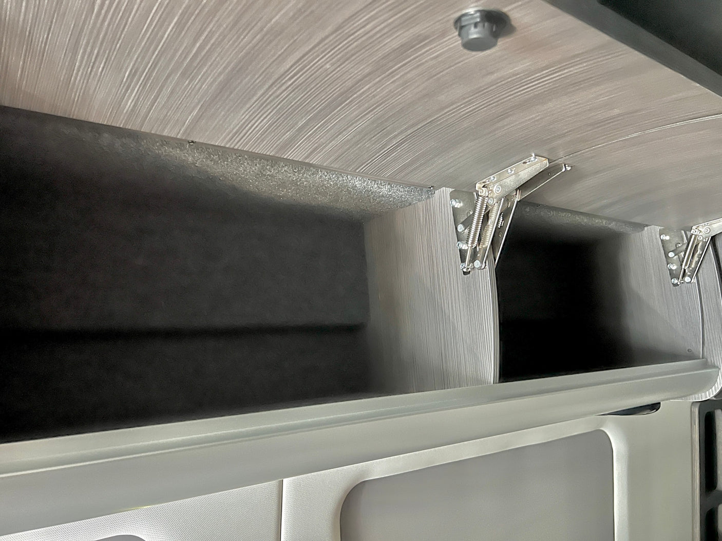 comfortable bed with pillows and a compact kitchenette.|Inside an RV rental: a compact bathroom featuring a white toilet