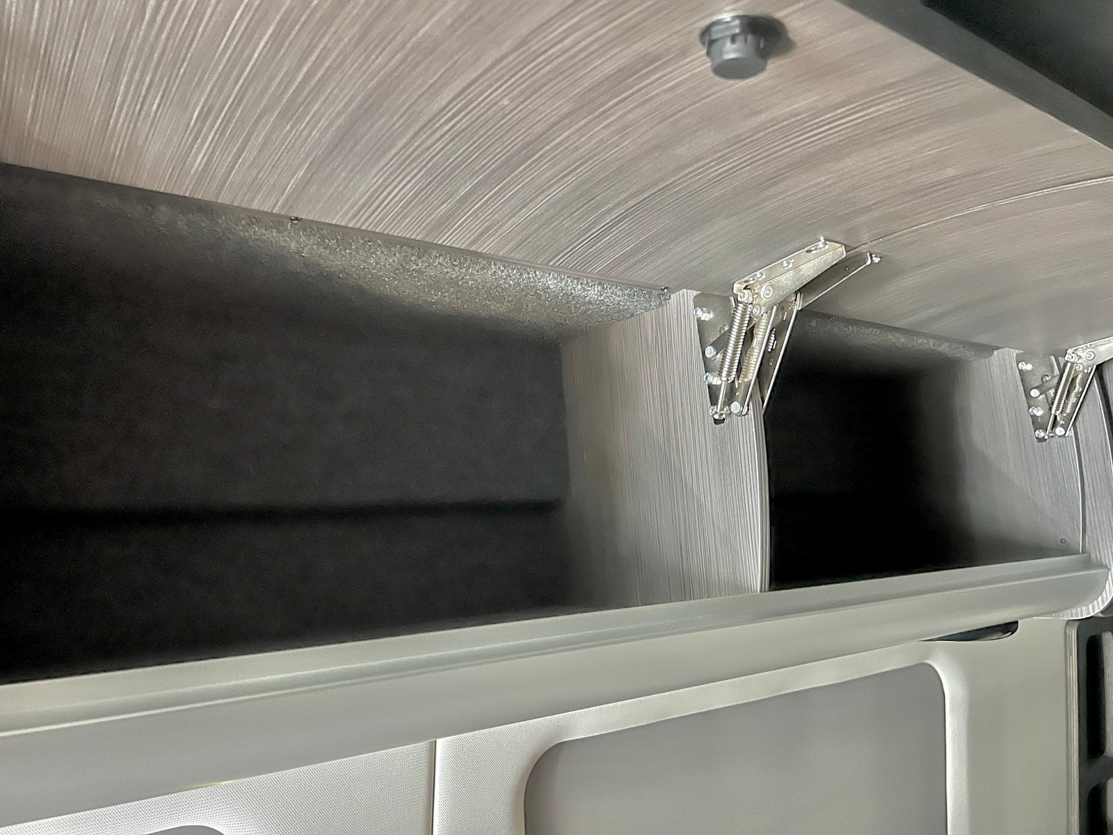 comfortable bed with pillows and a compact kitchenette.|Inside an RV rental: a compact bathroom featuring a white toilet