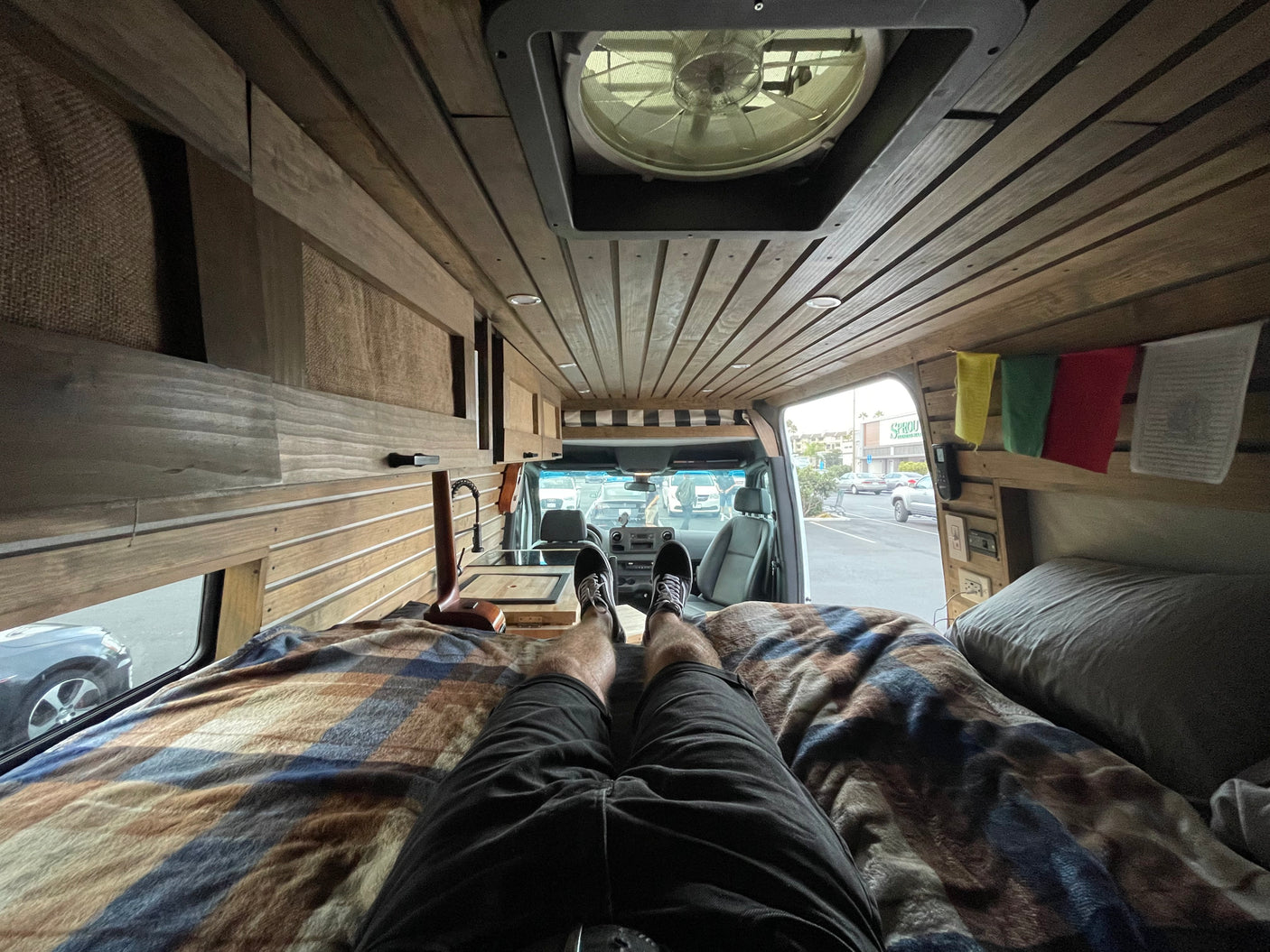 Kick back in a comfy RV rental! Enjoy this customized van's wood paneling, kitchenette, and outside view.