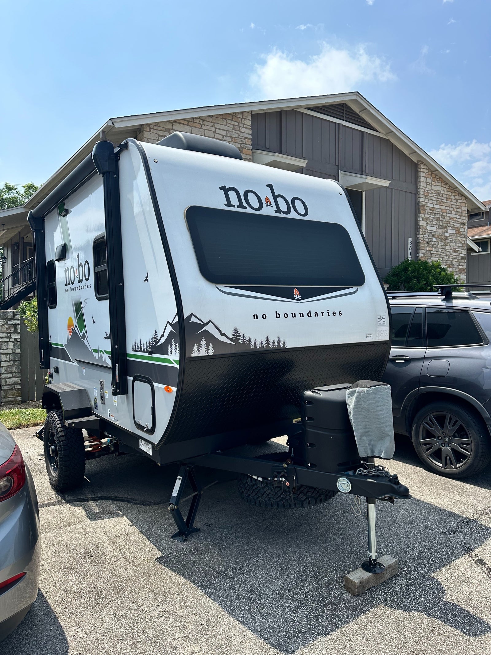 This white and black No Boundaries travel trailer, featuring mountain graphics, is ready for your next RV rental adventure.
