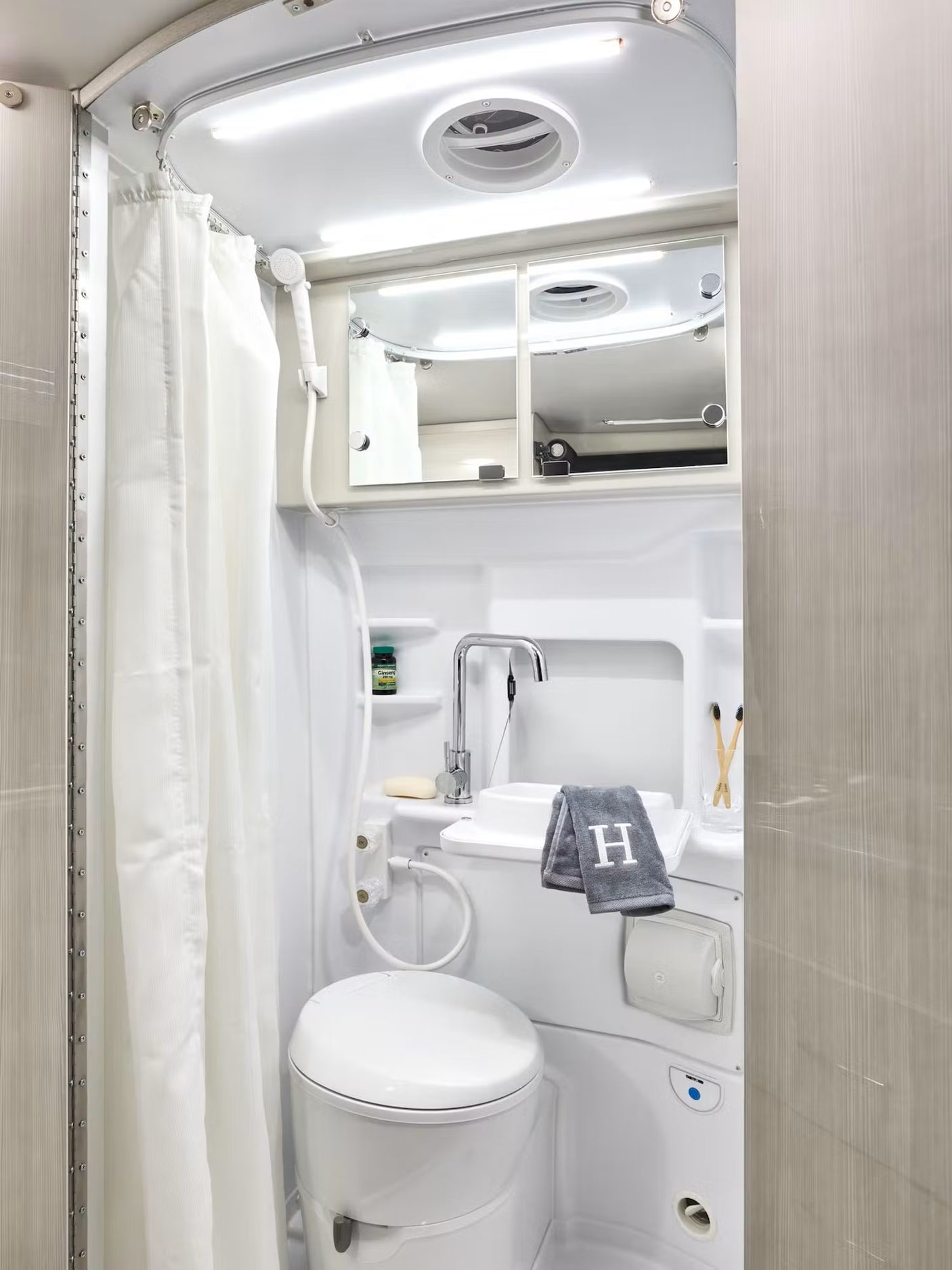 Explore comfort in your RV rental with this fully-equipped compact bathroom, featuring a toilet, sink, and shower.