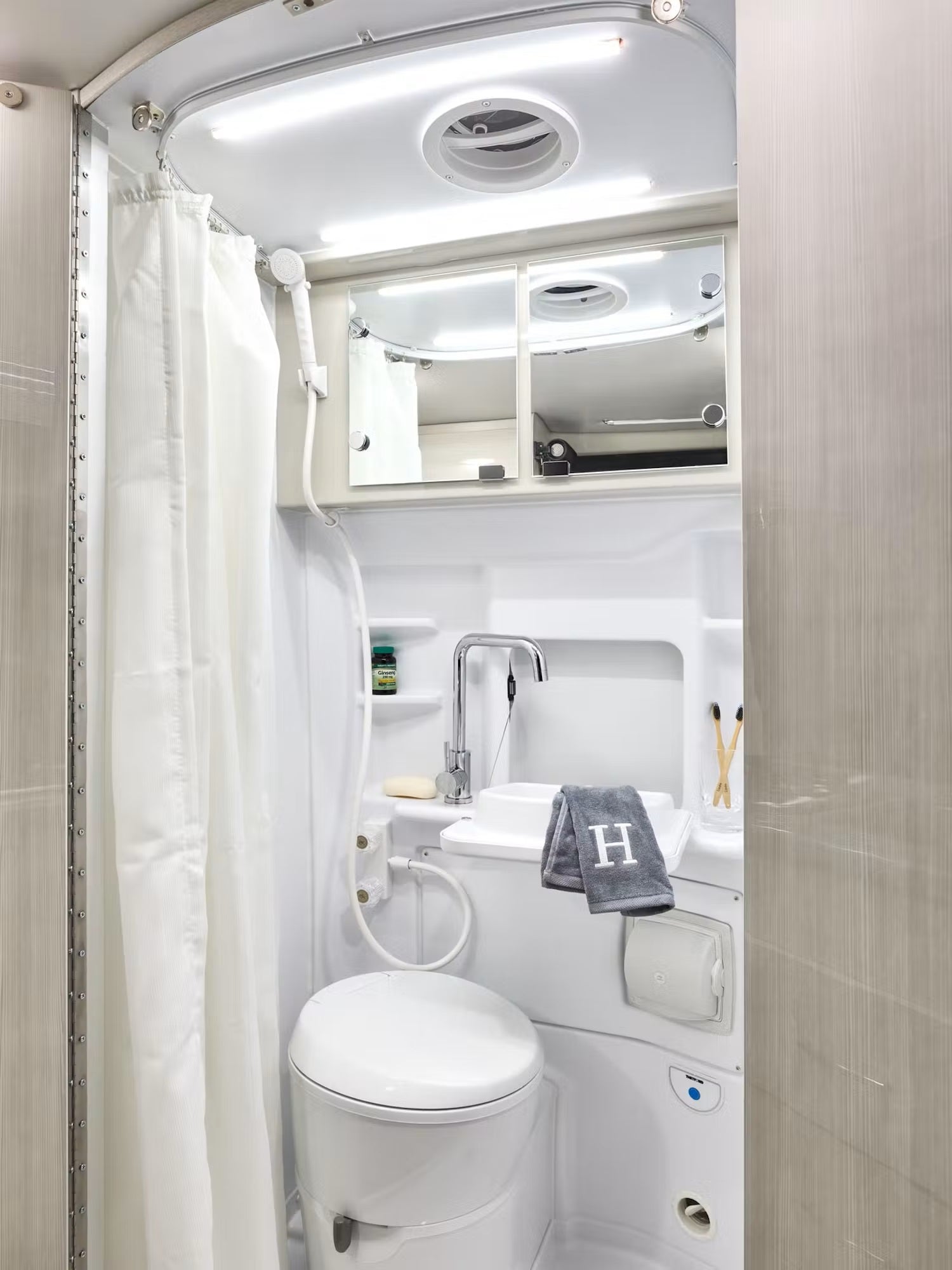 Explore comfort in your RV rental with this fully-equipped compact bathroom, featuring a toilet, sink, and shower.
