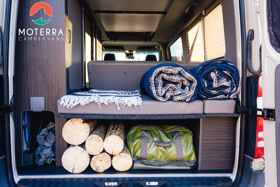 Moterrra Campervans RV rental: The organized interior features rolled blankets, stacked firewood, and gear storage.