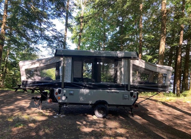 is ready for your next outdoor camping adventure.|Pop-up RV rental set up in a grassy field