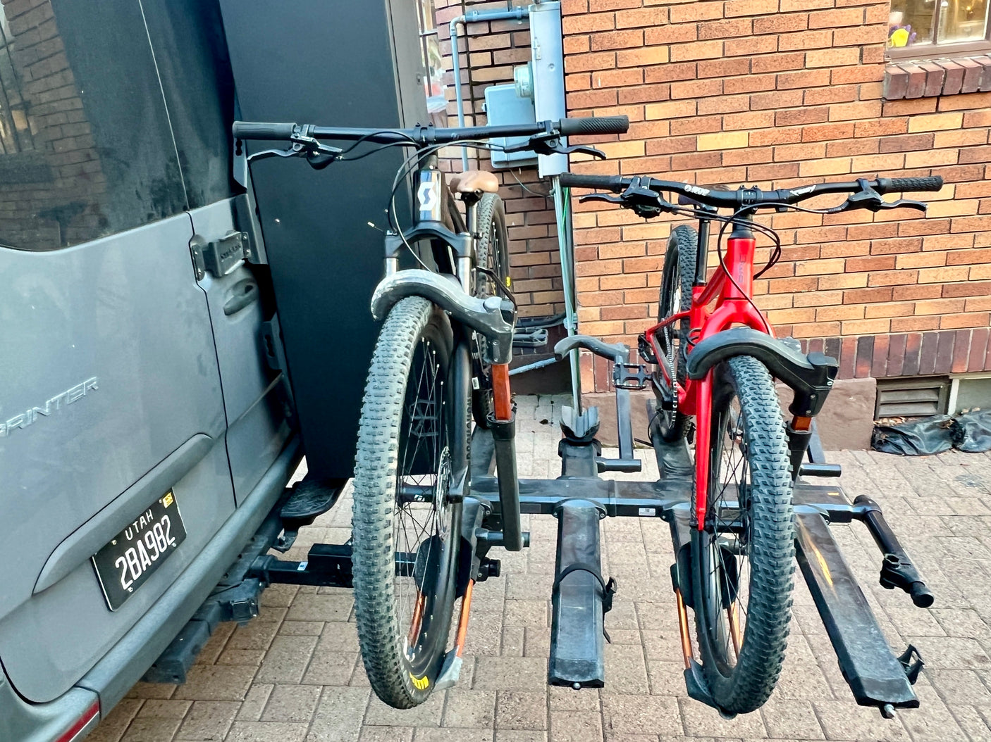 A gray Sprinter RV rental carries two mountain bikes on its rear rack, ready for Utah adventures.