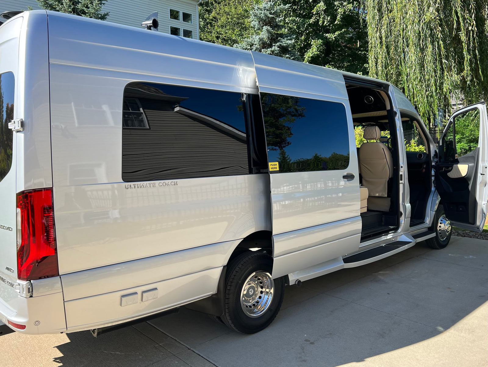 This sleek silver luxury van, ideal for your next rv rental, features an open side door, showcasing its plush interior.