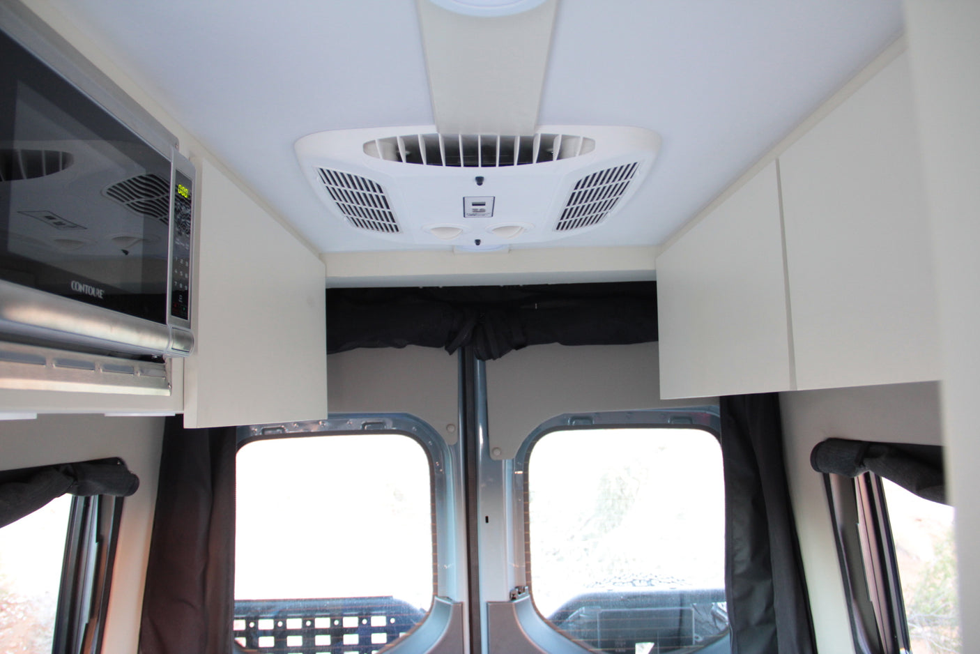 RV rental interior featuring microwave, air conditioning, and storage. Ideal for comfortable travel.
