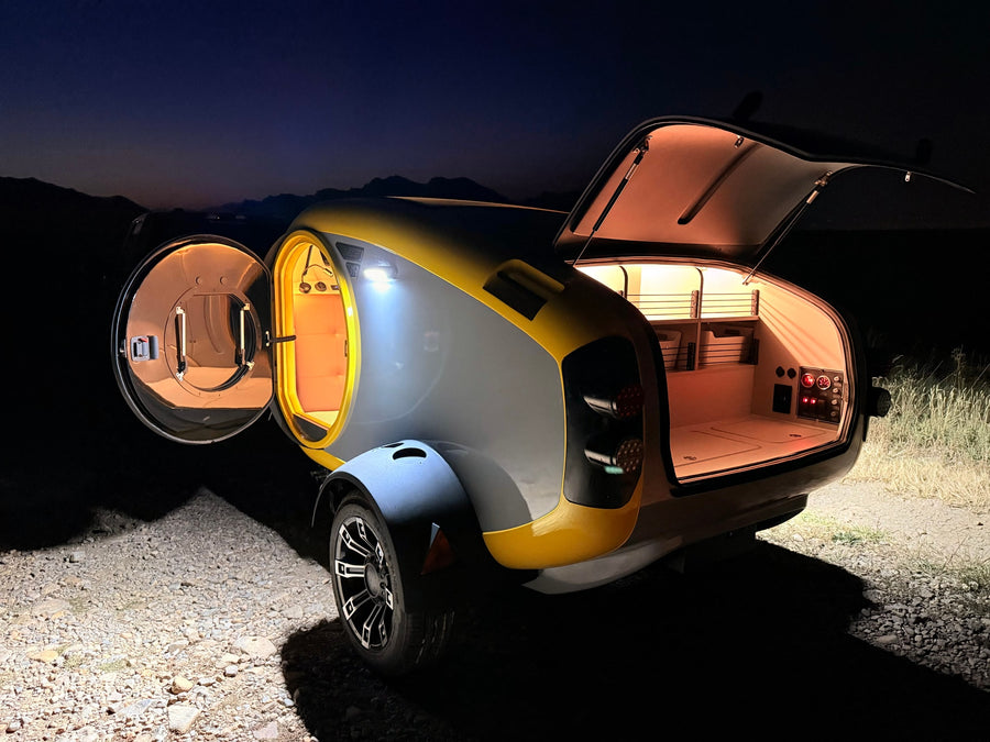 Sleek, illuminated compact camper with open doors revealing cozy interiors, ideal for an RV rental adventure under the night sky.