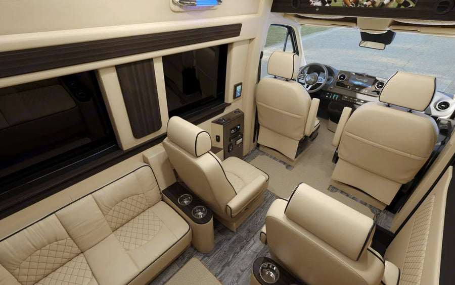 Spacious, luxurious RV rental interior with cream leather seating, integrated entertainment, and modern controls for ultimate comfort.