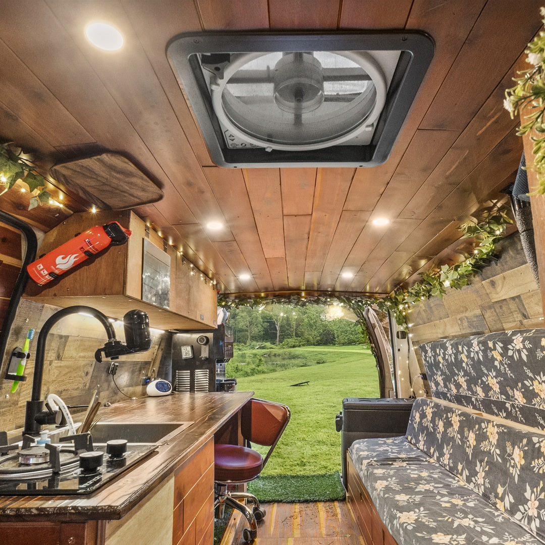 Explore nature with this RV rental! Cozy camper van interior features a kitchen, seating, and stunning outdoor view.