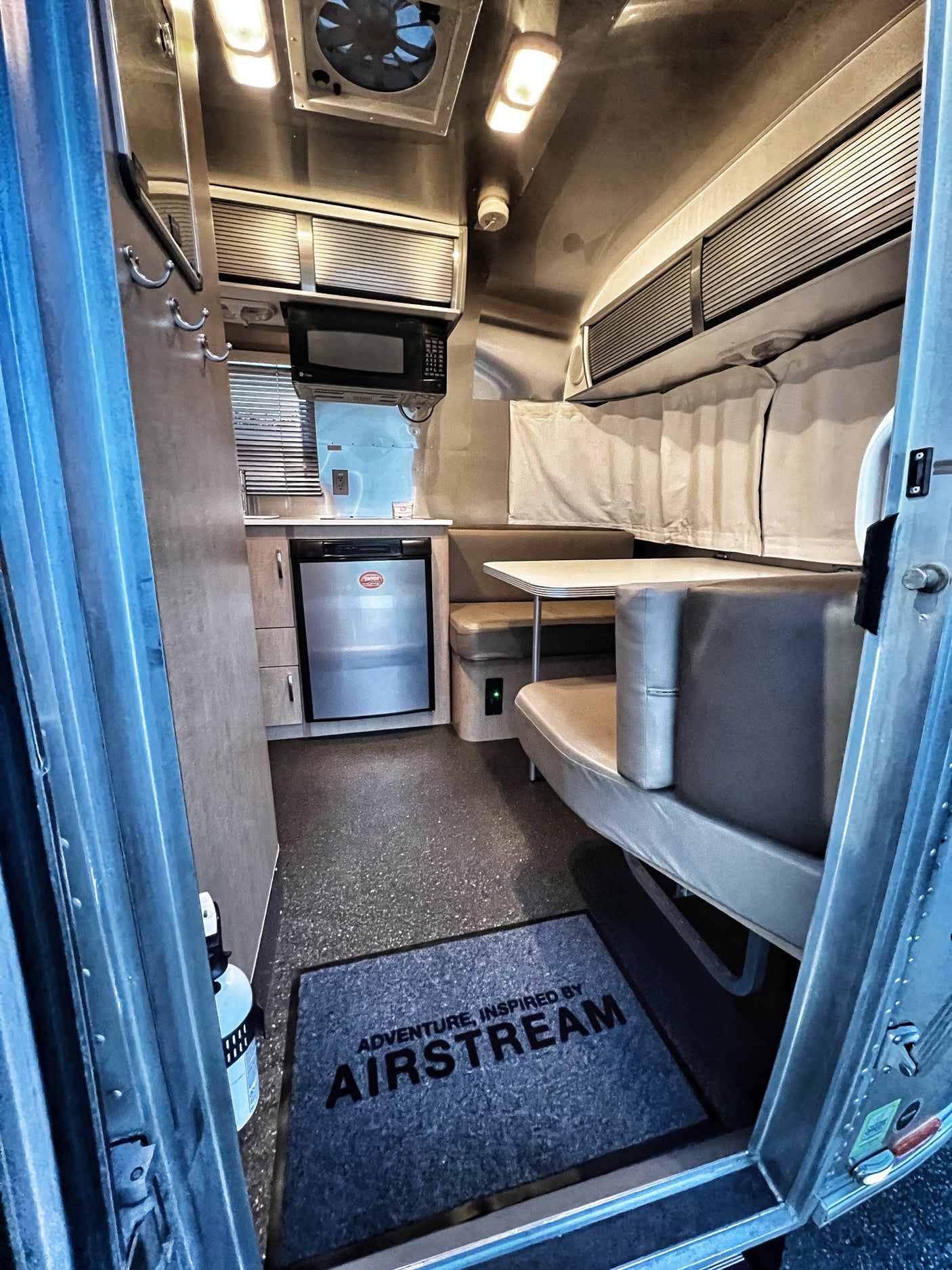 A bright Airstream RV rental interior, showcasing a compact kitchen, dining area, and comfortable seating for your road trip.