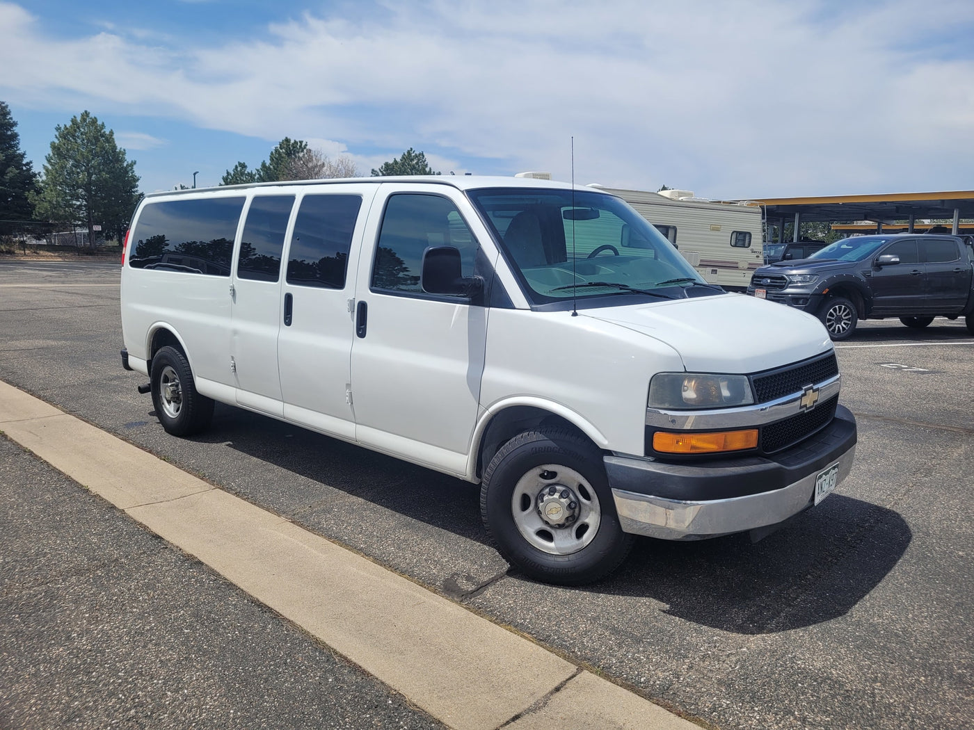 White Chevrolet Express van parked. A recreational vehicle (RV) and pickup truck are visible nearby, suggesting an RV rental site. — photo 8