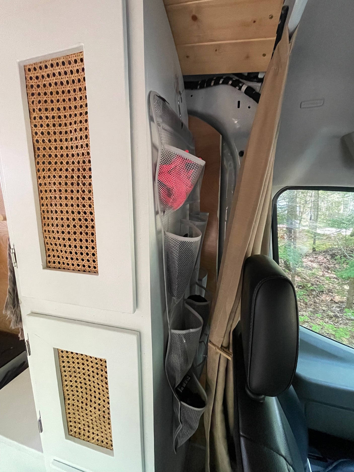ideal for an RV rental or camping trips.|Forest views from your RV rental kitchen. Modern sink area with unique pipe faucet in a cozy camper van interior.|RV rental cooler's interior: fresh green onions