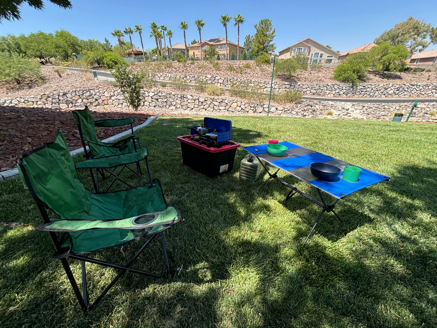 Backyard picnic setup: two green chairs, portable stove, and table on grass. Great for outdoor living after an RV rental adventure.