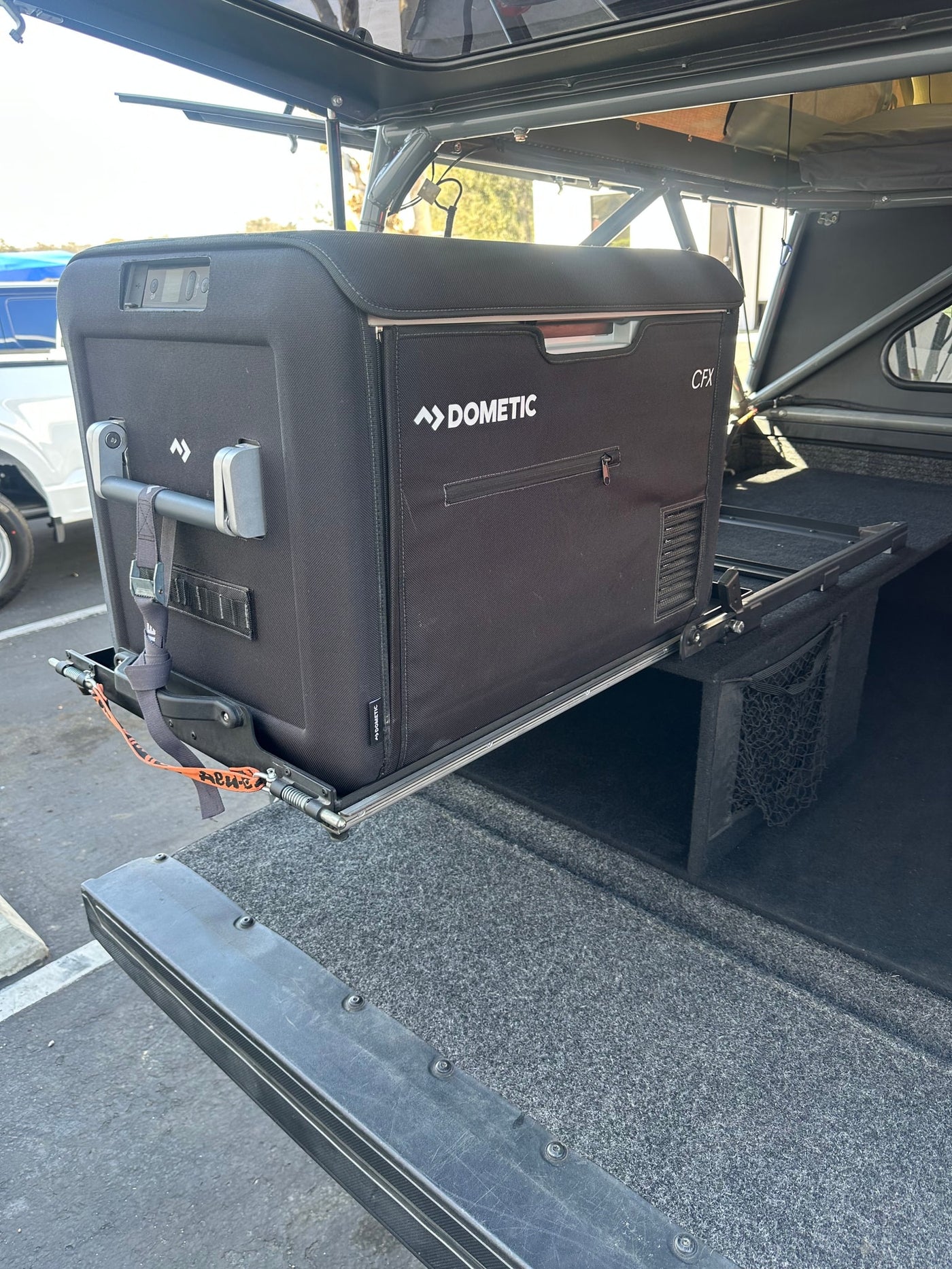 A black Dometic CFX portable fridge, extended on a slide-out tray from an RV rental vehicle for easy access during camping. — photo 15