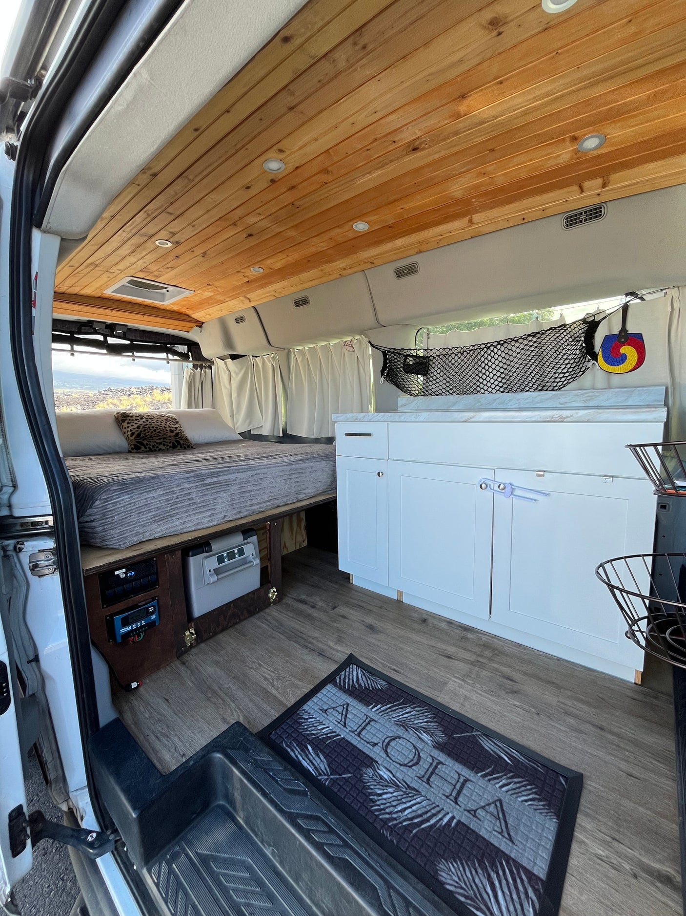 Cozy custom RV rental interior: wood ceiling, comfy bed, kitchen & storage. Perfect for your next adventure!