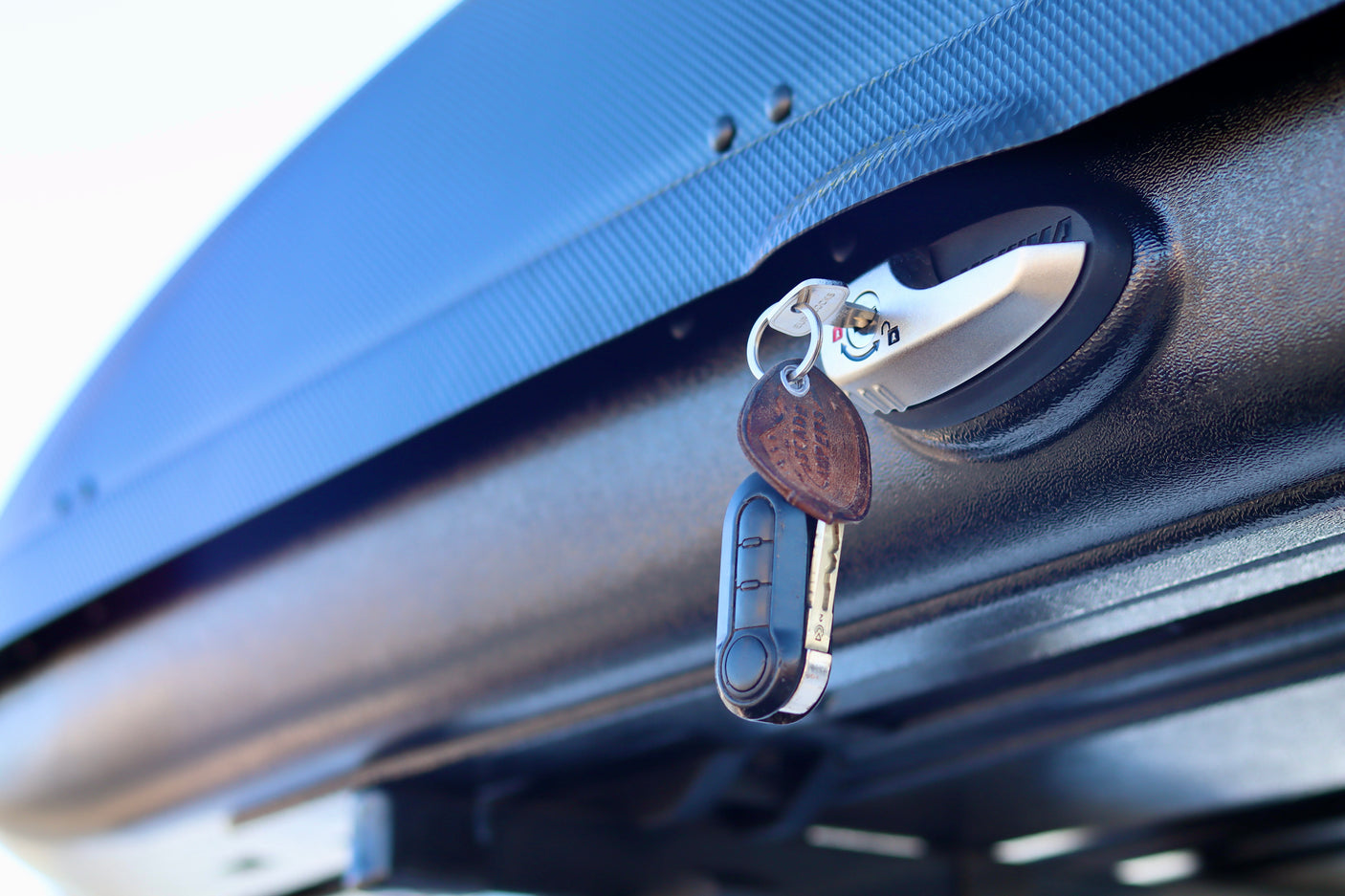 Key in lock of a textured black cargo box, commonly used on an RV rental, highlighting secure travel storage.